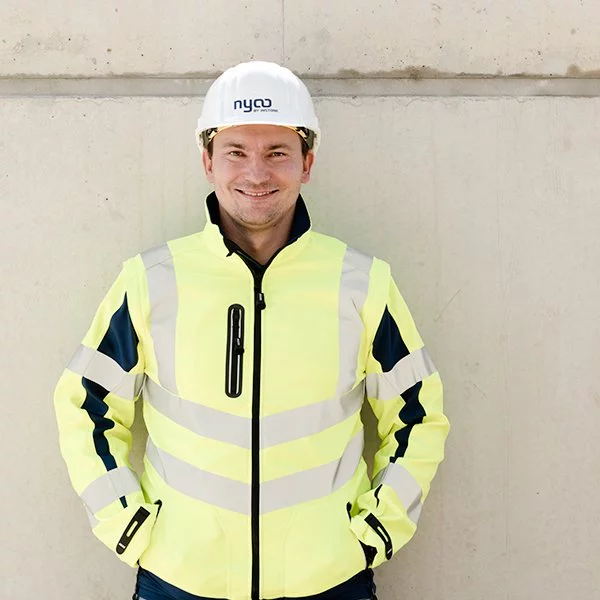 nyoo-Mitarbeiter Vjekoslav Kahlina in Arbeitskleidung und mit Helm mit der Aufschrift "nyoo BY INSTONE".