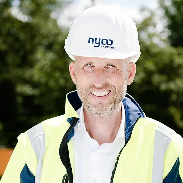 nyoo-Projektmanager Andreas Vogt in Arbeitskleidung und mit Helm mit der Aufschrift "nyoo BY INSTONE".