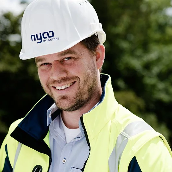 nyoo-Projektmanager Philipp Tappe in Arbeitskleidung und mit Helm mit der Aufschrift "nyoo BY INSTONE".